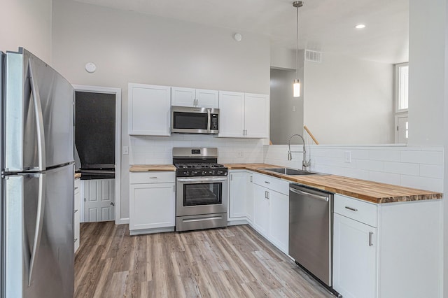 1335 Knapp St NE, Grand Rapids, MI 49505 - kitchen featuring appliances with stainless steel finishes, butcher block countertops, a sink, light wood finished floors, and white cabinets