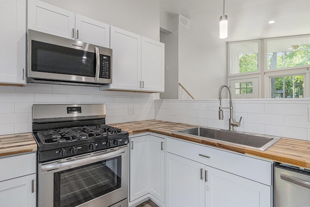 1335 Knapp St NE, Grand Rapids, MI 49505 - kitchen featuring stainless steel appliances, wood counters, a sink, tasteful backsplash, and white cabinetry