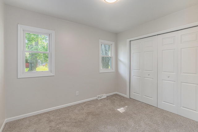 1335 Knapp St NE, Grand Rapids, MI 49505 - unfurnished bedroom featuring carpet floors, multiple windows, a closet, and baseboards