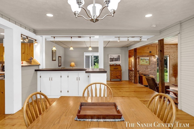 7120 Quarterline Rd, Spring Lake, MI 49456 - dining room with light wood-type flooring, a chandelier, wooden walls, and brick wall