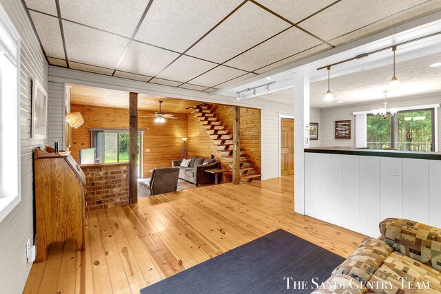 7120 Quarterline Rd, Spring Lake, MI 49456 - living area featuring wood-type flooring, wood walls, ceiling fan, stairway, and a chandelier