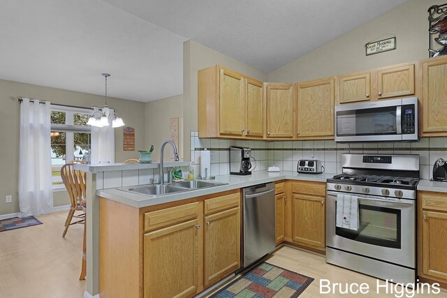 614 Oriole Ct Unit 7, Middleville, MI 49333 - kitchen with stainless steel appliances, a sink, a peninsula, light wood finished floors, and a chandelier