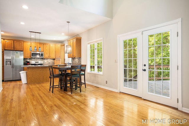 2103 Woodlark Dr, Holland, MI 49424 - kitchen with appliances with stainless steel finishes, decorative backsplash, hanging light fixtures, light wood finished floors, and dark countertops
