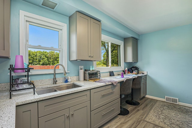 18422 Merriman Rd, Romulus, MI 48174 - kitchen featuring gray cabinets, a sink, wood finished floors, and light stone countertops