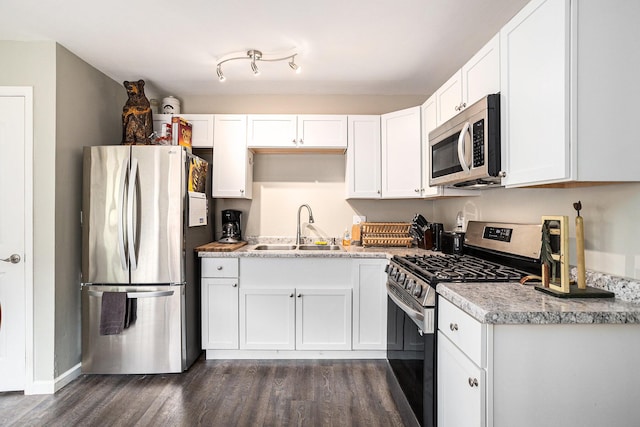 84 Eldred St, Battle Creek, MI 49015 - kitchen with appliances with stainless steel finishes, a sink, dark wood-style flooring, white cabinets, and baseboards