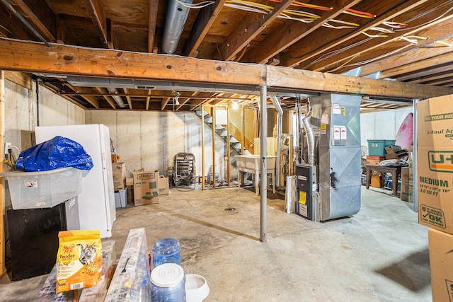 84 Eldred St, Battle Creek, MI 49015 - unfinished below grade area featuring heating unit, freestanding refrigerator, and stairs