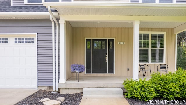 9340 Freedom Dr, West Olive, MI 49460 - view of exterior entry featuring a porch, a garage, and a shingled roof