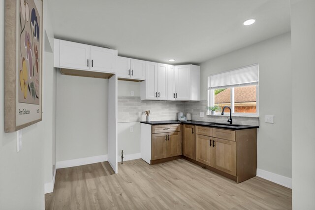 20504 Cherrylawn St, Detroit, MI 48221 - kitchen featuring a sink, light wood-style flooring, decorative backsplash, dark countertops, and baseboards
