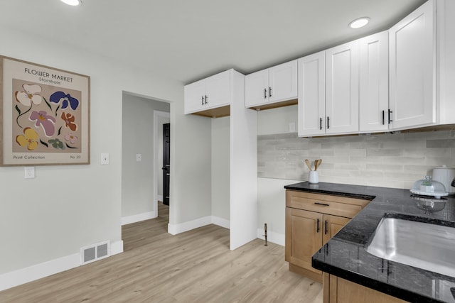 20504 Cherrylawn St, Detroit, MI 48221 - kitchen featuring dark stone countertops, light wood-type flooring, tasteful backsplash, baseboards, and white cabinets