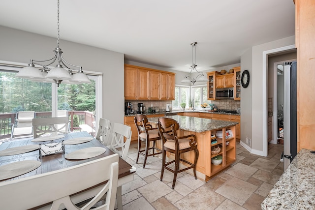 71 Knorrwood Dr, Rochester Hills, MI 48306 - kitchen featuring stainless steel microwave, decorative backsplash, light stone counters, stone tile flooring, and a kitchen breakfast bar