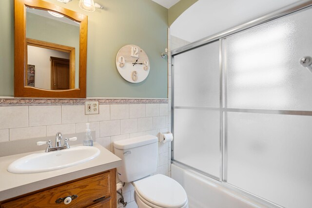 43 W Cherry Ave, Zeeland, MI 49464 - bathroom with vanity, toilet, shower / bath combination with glass door, tile walls, and wainscoting