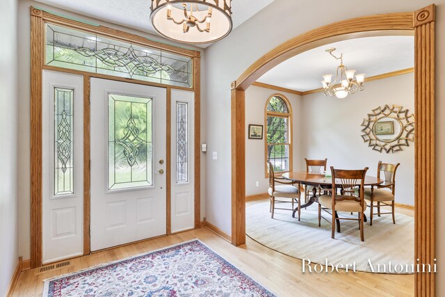6374 Blakely Dr NE, Rockford, MI 49341 - entrance foyer with a chandelier, arched walkways, wood finished floors, baseboards, and crown molding