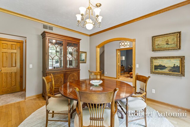 6374 Blakely Dr NE, Rockford, MI 49341 - dining area with arched walkways, light wood-style flooring, baseboards, a chandelier, and ornamental molding