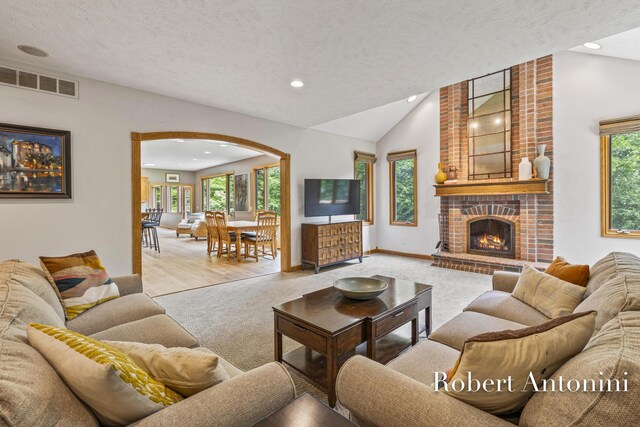 6374 Blakely Dr NE, Rockford, MI 49341 - carpeted living room featuring lofted ceiling, healthy amount of natural light, recessed lighting, a textured ceiling, and a fireplace