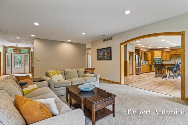 6374 Blakely Dr NE, Rockford, MI 49341 - living room with arched walkways, light colored carpet, recessed lighting, and baseboards