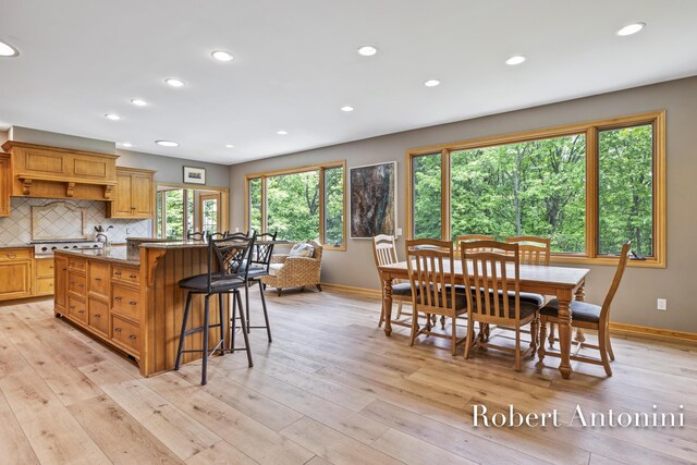 6374 Blakely Dr NE, Rockford, MI 49341 - kitchen featuring baseboards, light wood-style flooring, a kitchen bar, an island with sink, and recessed lighting