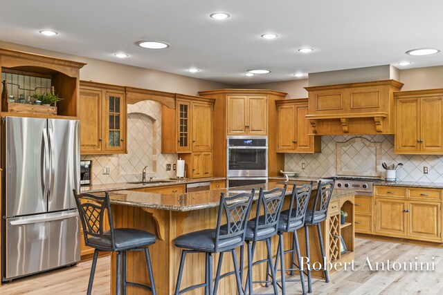 6374 Blakely Dr NE, Rockford, MI 49341 - kitchen with appliances with stainless steel finishes, stone counters, a sink, brown cabinetry, and light wood-style floors