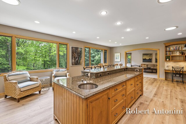 6374 Blakely Dr NE, Rockford, MI 49341 - kitchen featuring a sink, light wood-style floors, an island with sink, dark stone countertops, and recessed lighting