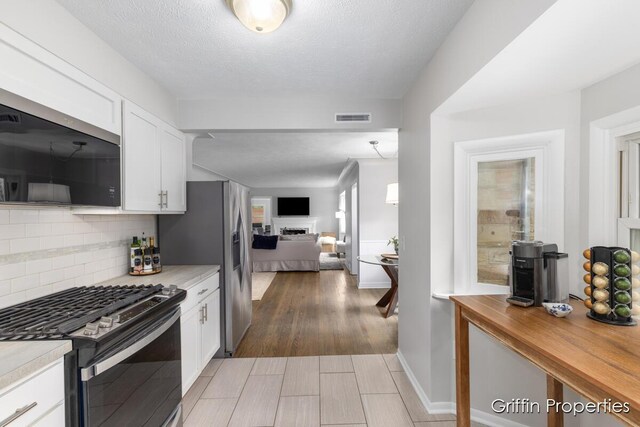 3020 Cascade Rd SE, Grand Rapids, MI 49506 - kitchen featuring stainless steel appliances, a fireplace, decorative backsplash, white cabinets, and open floor plan