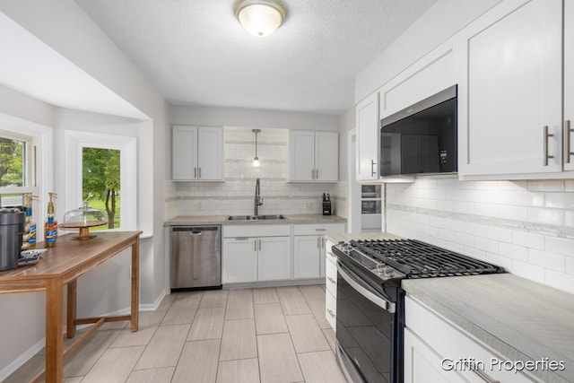 3020 Cascade Rd SE, Grand Rapids, MI 49506 - kitchen with appliances with stainless steel finishes, a sink, light countertops, decorative backsplash, and a textured ceiling