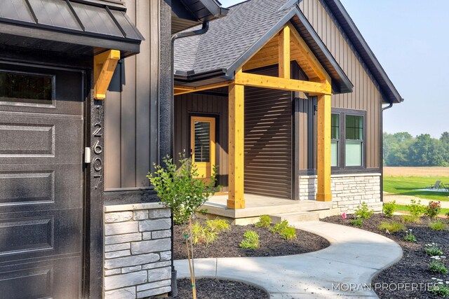 12607 76th Ave, Allendale, MI 49401 - doorway to property featuring stone siding, board and batten siding, a shingled roof, and a porch