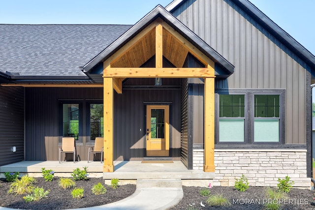 12607 76th Ave, Allendale, MI 49401 - view of exterior entry with covered porch, stone siding, a shingled roof, and board and batten siding