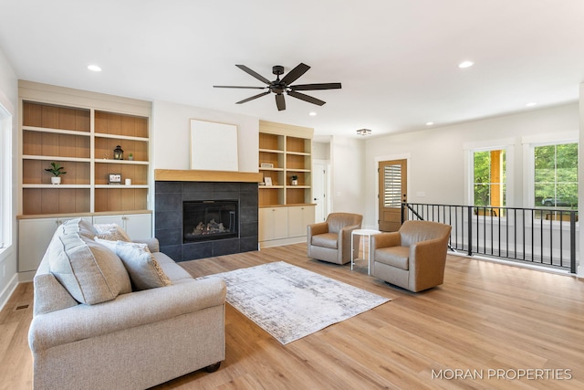 12607 76th Ave, Allendale, MI 49401 - living room featuring wood finished floors, a ceiling fan, a tile fireplace, recessed lighting, and built in shelves