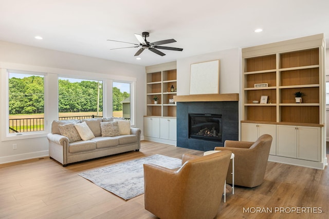 12607 76th Ave, Allendale, MI 49401 - living room with wood finished floors, a ceiling fan, a tile fireplace, baseboards, and built in shelves