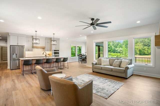 12607 76th Ave, Allendale, MI 49401 - living area with baseboards, recessed lighting, a ceiling fan, light wood-style flooring, and a chandelier