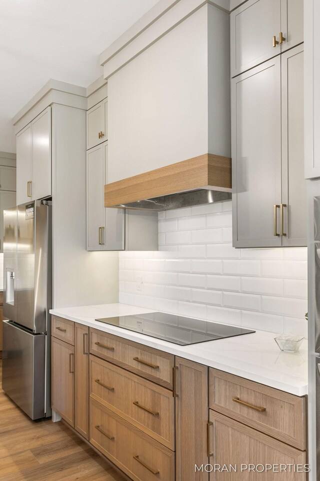 12607 76th Ave, Allendale, MI 49401 - kitchen featuring stainless steel fridge, custom range hood, black electric cooktop, decorative backsplash, and light countertops