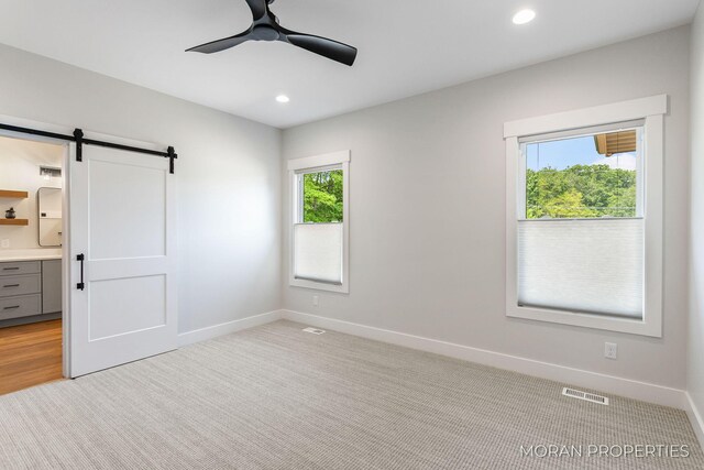 12607 76th Ave, Allendale, MI 49401 - unfurnished bedroom with baseboards, a barn door, recessed lighting, ensuite bath, and ceiling fan