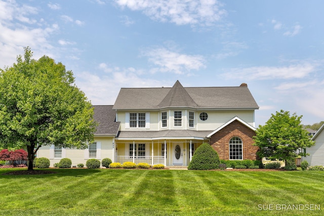 933 Meadow Ridge Dr, Holland, MI 49424 - victorian house with a porch, a front yard, a shingled roof, and brick siding