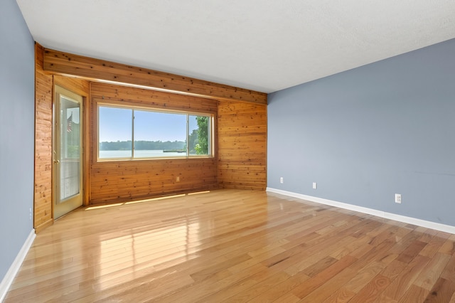 125 Wa Wee Nork Dr Unit 109-5-A, Battle Creek, MI 49015 - unfurnished room featuring wood walls, light wood-style floors, and baseboards