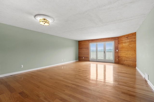 125 Wa Wee Nork Dr Unit 109-5-A, Battle Creek, MI 49015 - unfurnished room with wood walls, light wood-type flooring, a textured ceiling, and baseboards