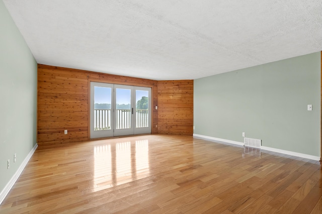 125 Wa Wee Nork Dr Unit 109-5-A, Battle Creek, MI 49015 - empty room featuring light wood-style flooring, wooden walls, a textured ceiling, and baseboards