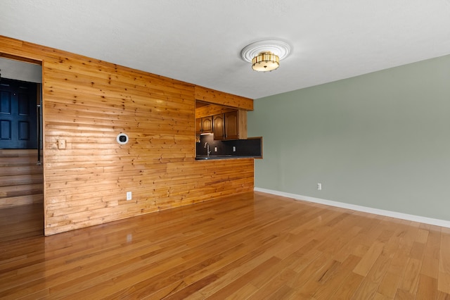 125 Wa Wee Nork Dr Unit 109-5-A, Battle Creek, MI 49015 - unfurnished living room with wood walls, light wood-style floors, and baseboards