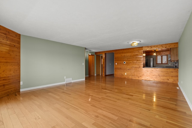 125 Wa Wee Nork Dr Unit 109-5-A, Battle Creek, MI 49015 - unfurnished living room with wood walls, light wood-style flooring, and baseboards