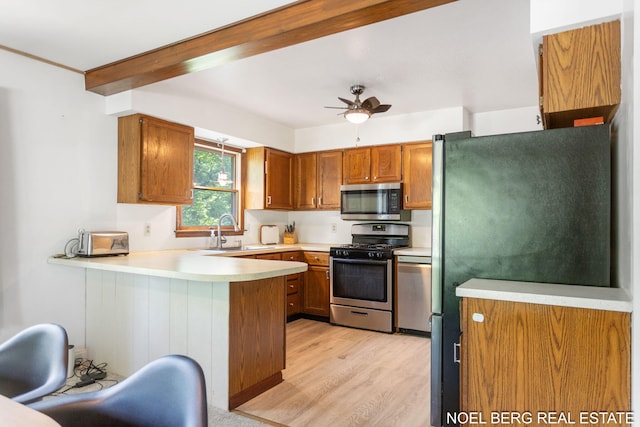 1710 Dykhouse Ave, Grand Haven, MI 49417 - kitchen with stainless steel appliances, a peninsula, a sink, light wood-style floors, and brown cabinetry