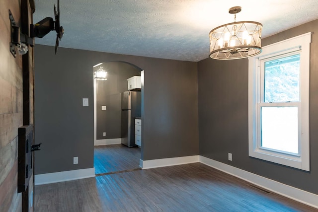 67679 Union Rd, Union, MI 49130 - empty room featuring arched walkways, dark wood-style floors, a textured ceiling, a chandelier, and baseboards