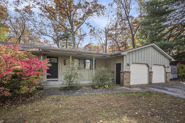 7362 30th St SE, Ada, MI 49301 - mid-century modern home featuring board and batten siding, a porch, a garage, and brick siding