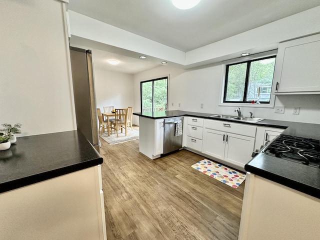 7362 30th St SE, Ada, MI 49301 - kitchen with appliances with stainless steel finishes, dark countertops, a peninsula, light wood-style flooring, and white cabinetry