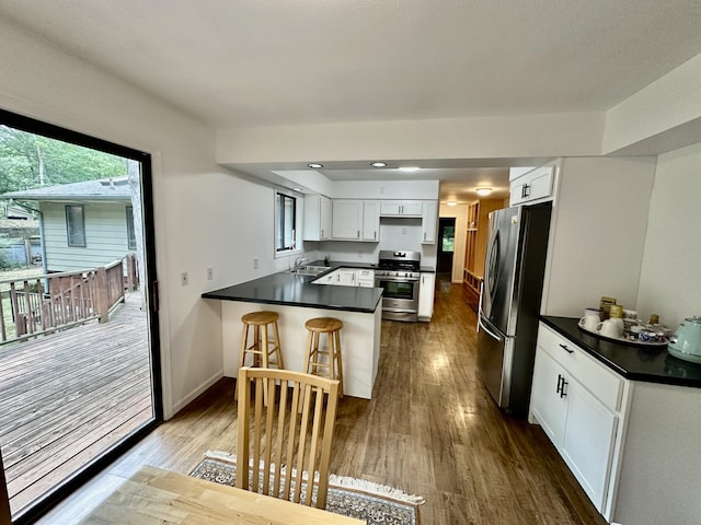 7362 30th St SE, Ada, MI 49301 - kitchen with appliances with stainless steel finishes, a peninsula, dark countertops, and dark wood-type flooring