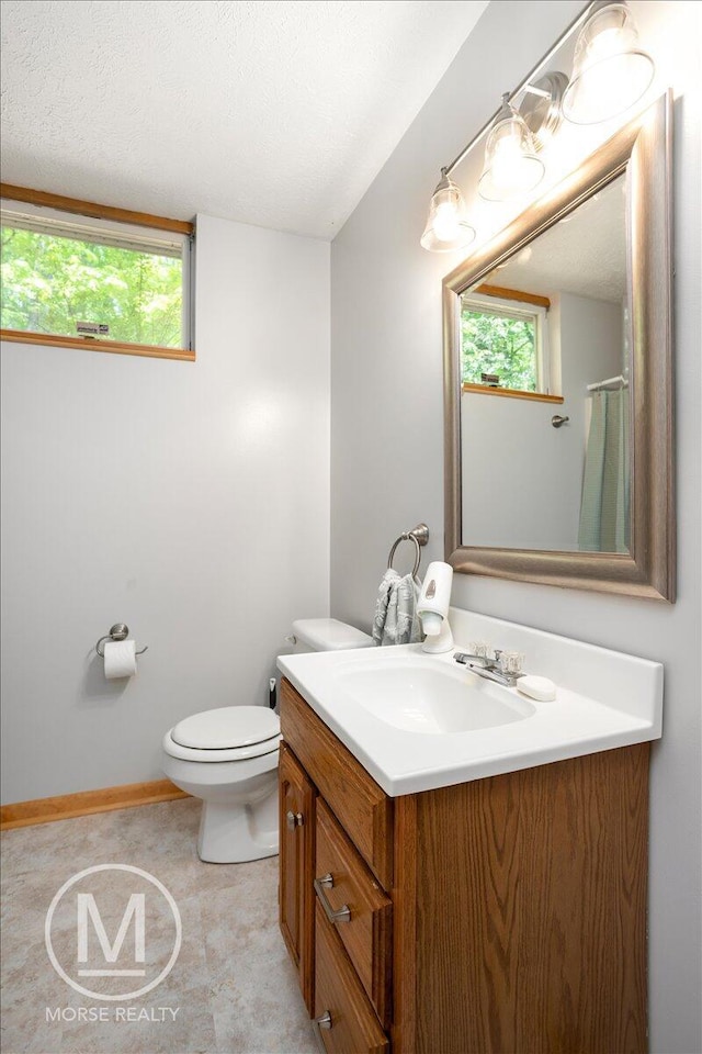 9057 Vergennes St SE, Ada, MI 49301 - bathroom with vanity, toilet, baseboards, and a textured ceiling