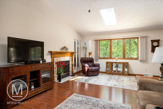 9057 Vergennes St SE, Ada, MI 49301 - living area with wood finished floors, a tile fireplace, a textured ceiling, lofted ceiling, and baseboards