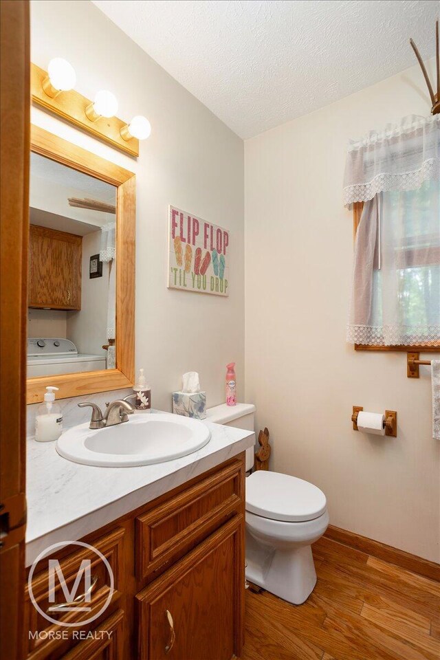 9057 Vergennes St SE, Ada, MI 49301 - bathroom featuring wood finished floors, vanity, toilet, a textured ceiling, and baseboards