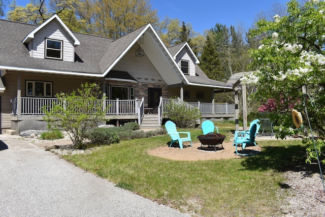 226 N 176th Ave, Walkerville, MI 49459 - view of front facade with a fire pit, a front yard, stone siding, and roof with shingles