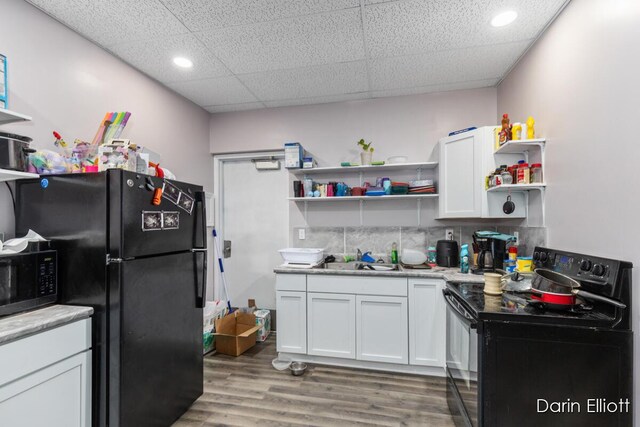 306 W Russell St, Hubbardston, MI 48845 - kitchen with black appliances, open shelves, light countertops, light wood-style flooring, and white cabinetry