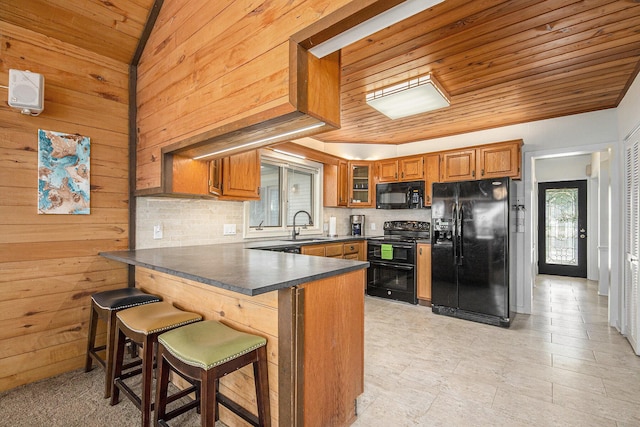 8994 Lenhards Lndg, Clarksville, MI 48815 - kitchen featuring black appliances, a peninsula, brown cabinetry, decorative backsplash, and dark countertops