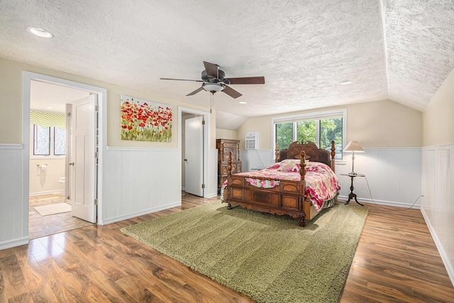 8994 Lenhards Lndg, Clarksville, MI 48815 - bedroom featuring a wainscoted wall, a textured ceiling, wood finished floors, connected bathroom, and lofted ceiling