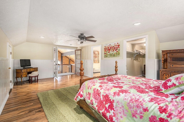 8994 Lenhards Lndg, Clarksville, MI 48815 - bedroom featuring a textured ceiling, wainscoting, wood finished floors, vaulted ceiling, and a spacious closet